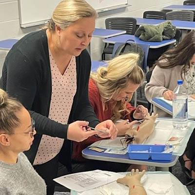 faculty with students in classroom working on bandaging